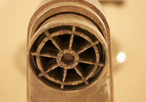A bathtub faucet with built-up calcification from hard water.